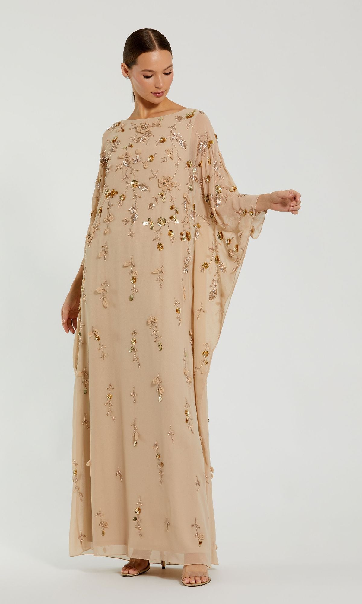A woman stands against a plain background wearing the Trapeze Embellished Formal Gown—Mac Duggal 9242, a long gold dress with floral embroidery.